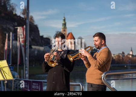 Salzbourg, Autriche - 27 décembre 2021 : deux joueurs de trompet qui jouent sur le pont de l'écluse de l'Amour à Salzbourg, Autriche. Banque D'Images