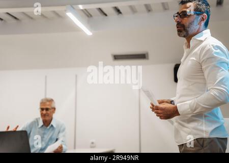 Vue latérale d'un homme d'affaires qui a une bonne apparence et qui a un discours dans la salle de classe. Il présente de nouvelles idées commerciales Banque D'Images