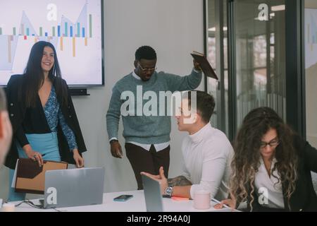 Beaucoup de gens d'affaires debout et assis dans la salle de conférence pendant que deux collègues d'affaires présentent Banque D'Images