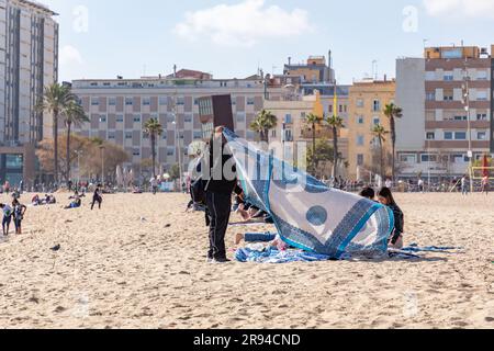 Barcelone, Espagne - 10 FÉVRIER 2022 : vendeurs illégaux de vêtements de plage sur la plage de Barceloneta. Banque D'Images
