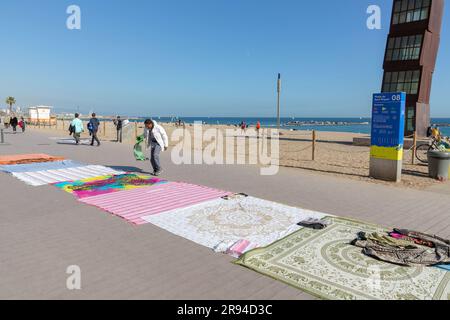 Barcelone, Espagne - 10 FÉVRIER 2022 : vendeurs illégaux de vêtements de plage sur la plage de Barceloneta. Banque D'Images