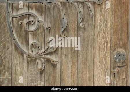 Un fragment d'une ancienne porte en bois avec un fragment d'une charnière décorative. Ancienne porte de l'église. Banque D'Images