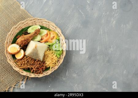 Nasi Uduk, riz salé indonésien cuit à la vapeur, cuit au lait de coco. Servi avec divers plats d'accompagnement et recouvert d'Ayam Goreng Banque D'Images