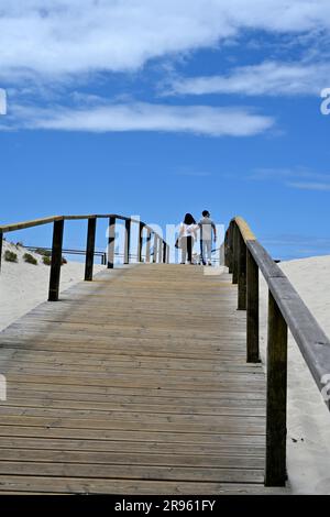 Couple à distance de marche sur la promenade en bois sur la plage de sable, Banque D'Images