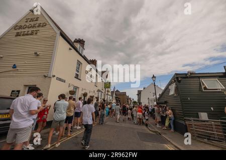 Leigh on Sea, Royaume-Uni. 24 juin 2023. Une foule de gens longe la rue étroite devant le Crooked billet, un pub historique à Leigh-on-Sea, Essex. Le ciel couvert et les nuages spectaculaires ajoutent de l'atmosphère à ce lieu de rassemblement populaire, suggérant un événement local ou une ruée de week-end. Les gens font la queue pour prendre un verre au Crooked billet. Les gens à Old Leigh on Sea apprécient le temps chaud. Penelope Barritt/Alamy Live News Banque D'Images