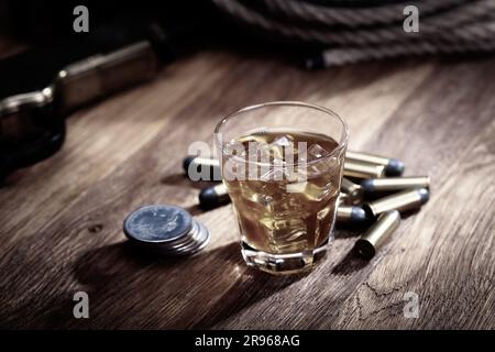 Whisky tiré avec glace et munitions avec pièces de monnaie anciennes en argent sur une table de bar en bois Banque D'Images