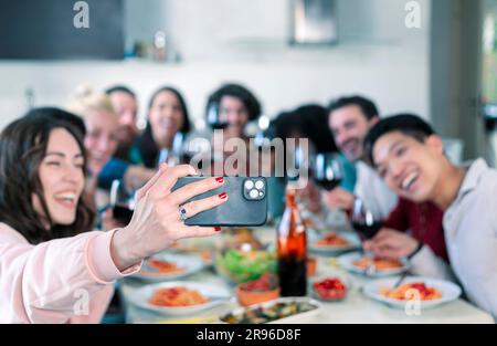 Groupe d'amis prenant des selfies pendant le déjeuner à l'intérieur Banque D'Images