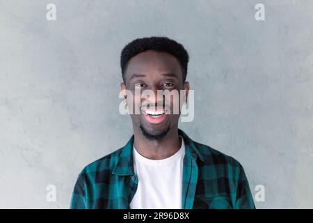 Beau jeune non rasé foncé, un homme rit en montrant ses dents blanches droites. Expressions et émotions positives du visage humain Banque D'Images
