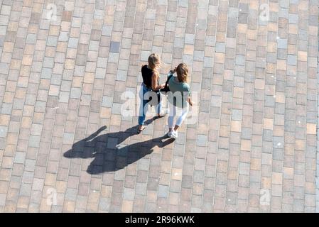 Deux femmes marchant dans un carré public jetant de longues ombres, vues depuis le sommet d'un grand bâtiment. Banque D'Images