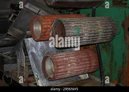 De grands rouleaux en métal roulent avec les dents des engrenages de la chaîne de production, un tapis convoyeur dans l'atelier d'une machine pétrochimique industrielle Banque D'Images