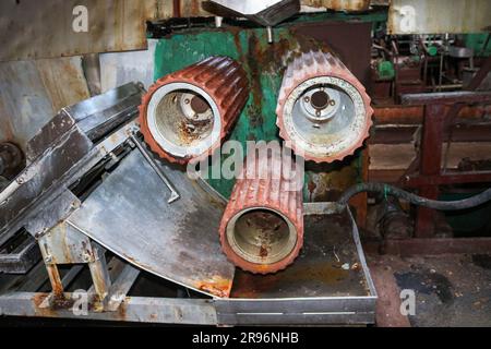 De grands rouleaux en métal roulent avec les dents des engrenages de la chaîne de production, un tapis convoyeur dans l'atelier d'une machine pétrochimique industrielle Banque D'Images