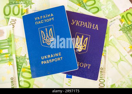 Deux passeports ukrainiens un est blessé par le deuxième passeport civil sur le fond des billets en euros à la valeur nominale de 100 Banque D'Images