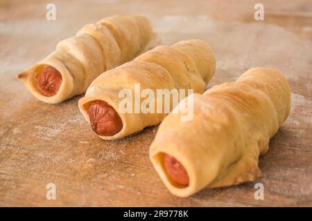 Trois petits pains avec saucisse sur fond horizontal en bois Banque D'Images