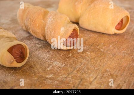 Trois petits pains avec saucisse sur fond horizontal en bois Banque D'Images