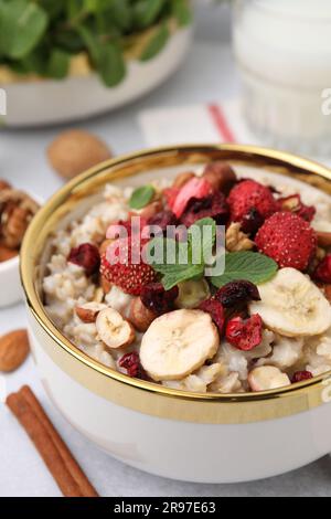 Délicieux flocons d'avoine avec baies lyophilisées, banane, noix et menthe sur la table, en gros plan Banque D'Images