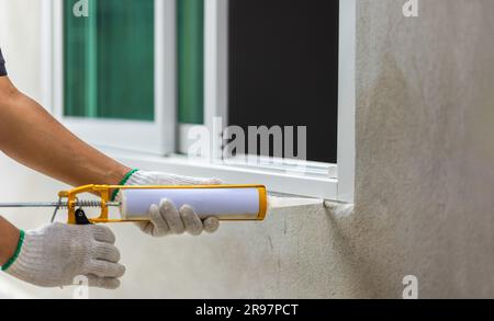 Le travailleur de la construction utilisant du produit d'étanchéité au silicone calfeutrer le cadre extérieur de la fenêtre. Banque D'Images