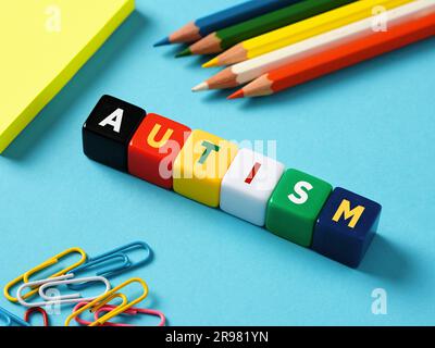 Autisme et concept d'éducation. Trouble du spectre de l'autisme. Le mot autisme sur des cubes colorés avec des objets de papeterie sur fond bleu. Banque D'Images