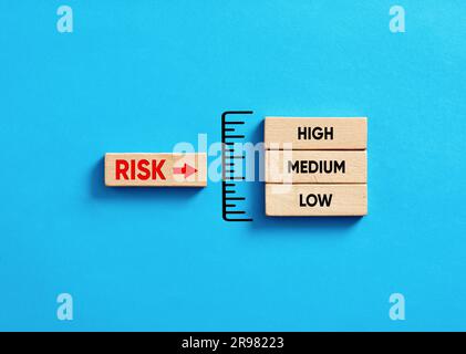 Prise de décision et analyse des risques. Gestion et évaluation des risques dans l'entreprise. Indicateur de niveau de risque avec blocs de bois sur fond bleu. Banque D'Images