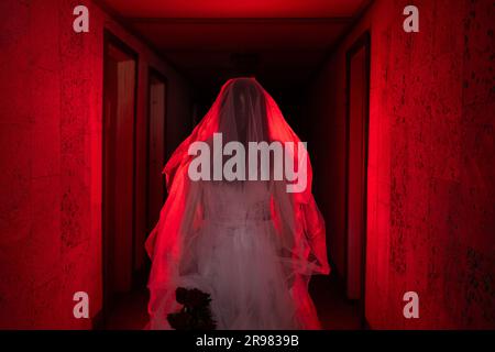 Scène d'horreur d'une mariée de cadavre debout dans une maison hantée à la lumière rouge. Halloween fête effrayante Banque D'Images