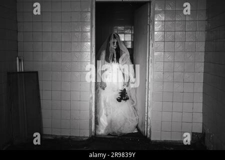 Histoire fantôme de mariée sur Halloween. Femme en robe blanche dans la maison abandonnée Banque D'Images