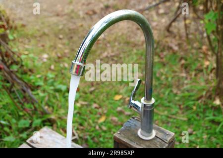 Gros plan de l'eau qui coule du robinet dans le jardin Banque D'Images