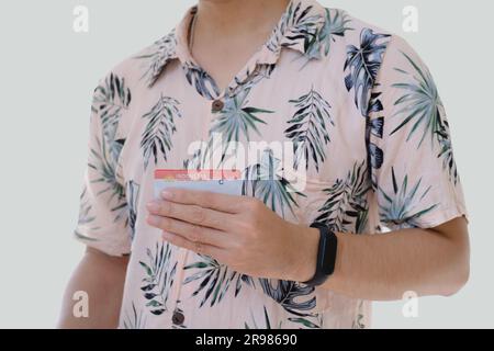 Un homme asiatique portant une chemise rose avec des motifs tropicaux tient Surat Ijin Mengemudi ou SIM C signifie permis de conduire indonésien pour moto Banque D'Images