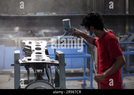 Djakarta, Indonésie - 20 juin 2023 : un homme en rouge peint le cadre de la voiture manuellement. Banque D'Images