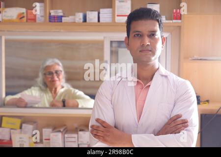 chimiste homme debout dans la pharmacie - pharmacie. Gros plan sur le pharmacien à la pharmacie hospitalière. Aider les clients, vieille dame client sur le comptoir. Banque D'Images