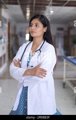 Portrait de femme médecin senior confiante avec les bras croisés. Heureux docteur en blouse blanche debout dans le couloir de l'hôpital. Banque D'Images