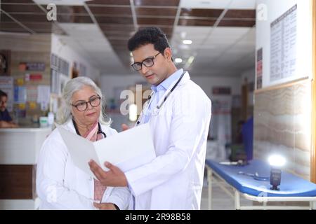 Femme médecin âgée et jeune homme médecin. Médecin lisant le rapport du patient sur la paperasse ou le document médical. Banque D'Images