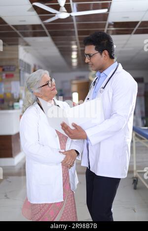 Femme médecin âgée et jeune homme médecin. Médecin lisant le rapport du patient sur la paperasse ou le document médical. Banque D'Images
