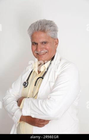 Médecin femme senior en blouse de laboratoire avec les bras croisés sur fond blanc. Heureux docteur indien en manteau blanc. confiant. Banque D'Images