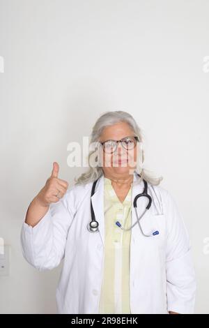 Médecin femme senior en blouse de laboratoire avec les bras croisés sur fond blanc. Heureux docteur indien en manteau blanc. confiant. Banque D'Images