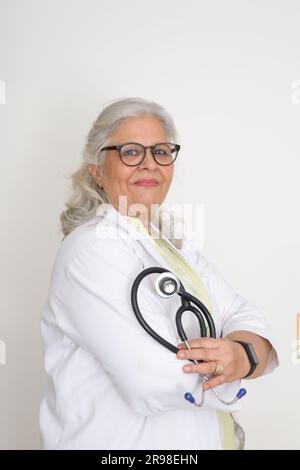 Médecin femme senior en blouse de laboratoire avec les bras croisés sur fond blanc. Heureux docteur indien en manteau blanc. confiant. Banque D'Images