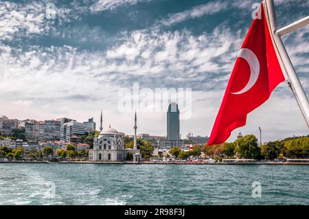 Vue sur la côte de Dolmabahce depuis un ferry traversant le Bosphore du côté européen vers l'Asie. Drapeau turc sur la gauche, Istanbul, Turquie. Banque D'Images