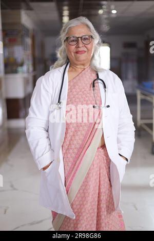 Portrait de femme médecin senior avec les bras croisés debout dans le couloir de l'hôpital. Heureux docteur indien blouse blanche de laboratoire Banque D'Images