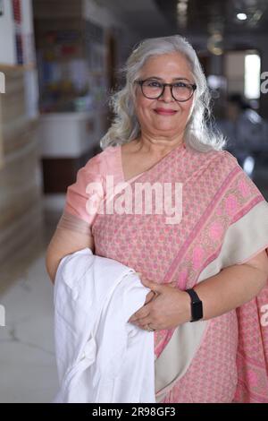 Portrait de femme médecin senior avec les bras croisés debout dans le couloir de l'hôpital. Heureux docteur indien blouse blanche de laboratoire Banque D'Images