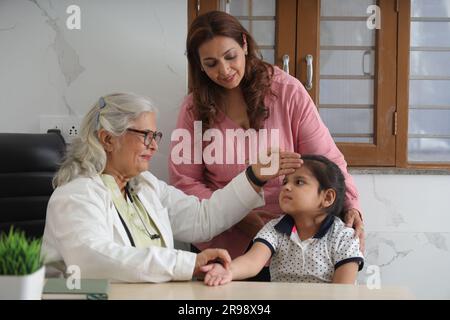 médecin de visite de famille heureuse pour consultation personnelle avec leur fille, fille à l'hôpital, check up, cabine, bureau, conscient de la santé, attention. Banque D'Images