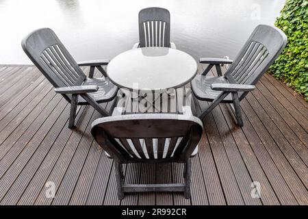 groupe de sièges sur la terrasse au bord de l'eau sous la pluie Banque D'Images