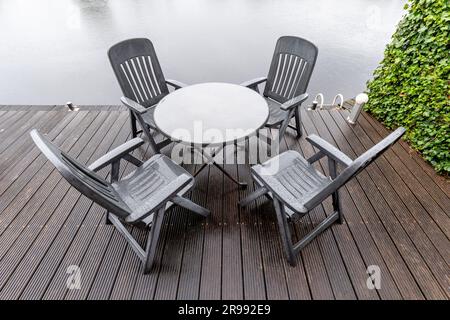 groupe de sièges sur la terrasse au bord de l'eau sous la pluie Banque D'Images