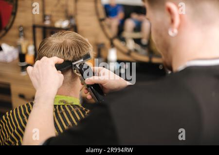 le coiffeur professionnel rasse les poils de l'homme au salon de coiffure. Vue arrière du client Banque D'Images