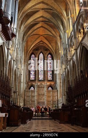 Les visiteurs se pontent sur l'intérieur charmant de la cathédrale de Truro, sur fond de la magnifique Reredod sculptée et de la fenêtre est. Banque D'Images