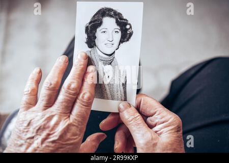 VERS 1970 : mains de femme âgée tenant une photo vintage, noire et blanche de la jeune femme. Concept de passage du temps Banque D'Images