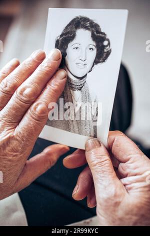 VERS 1970 : mains de femme âgée tenant une photo vintage, noire et blanche de la jeune femme. Concept de passage du temps Banque D'Images