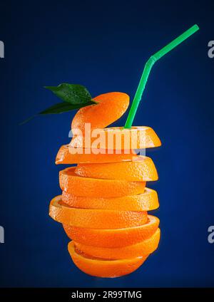 Agrumes frais sous forme de boisson rafraîchissante avec paille sur fond bleu foncé. Jus d'orange. photo publicitaire. Cocktail à base de tranches d'orange. Banque D'Images