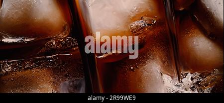 Cola avec glace. Gros plan des glaçons dans l'eau de cola. Texture de la boisson carbonate avec bulles dans le verre. Soda et glace éclaboussant ou flottant Banque D'Images