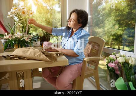 Femme enceinte travaillant arranger des fleurs, faisant une belle composition de fleurs dans un panier en osier à son propre magasin de fleurs Banque D'Images