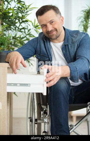 homme handicapé plaçant une chemise sur une étagère à la maison Banque D'Images