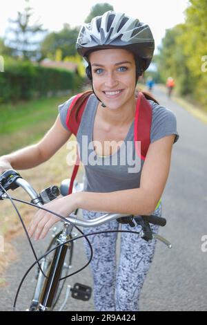 portrait d'une jeune femme penchée sur un vélo portant un casque Banque D'Images