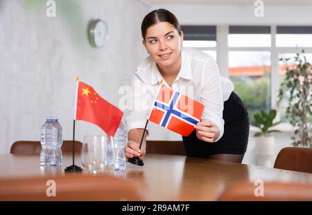 Préparer les négociations commerciales - la femme fixe de petits drapeaux sur la table des pays de la Chine et de la Norvège Banque D'Images